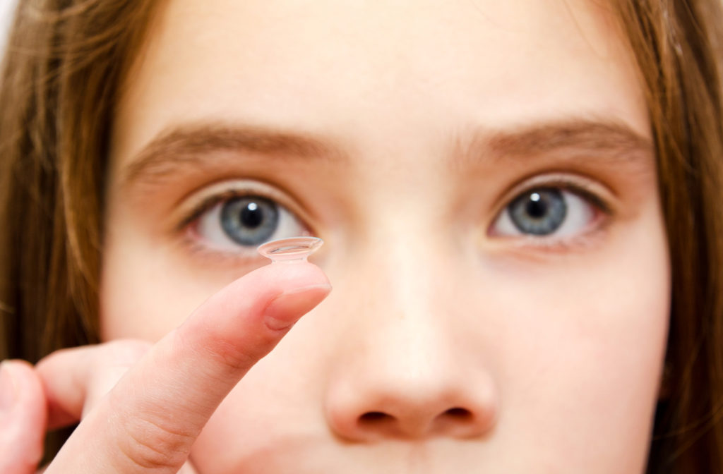Young girl looking at contact lenses before putting them on