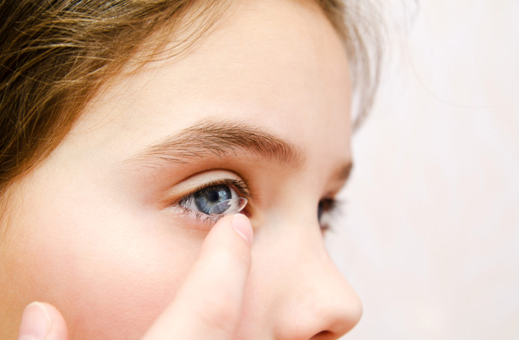 Young girl with blue eyes putting on contact lenses